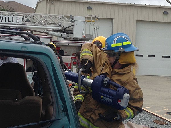 Student in firefighter uniform cutting into a car